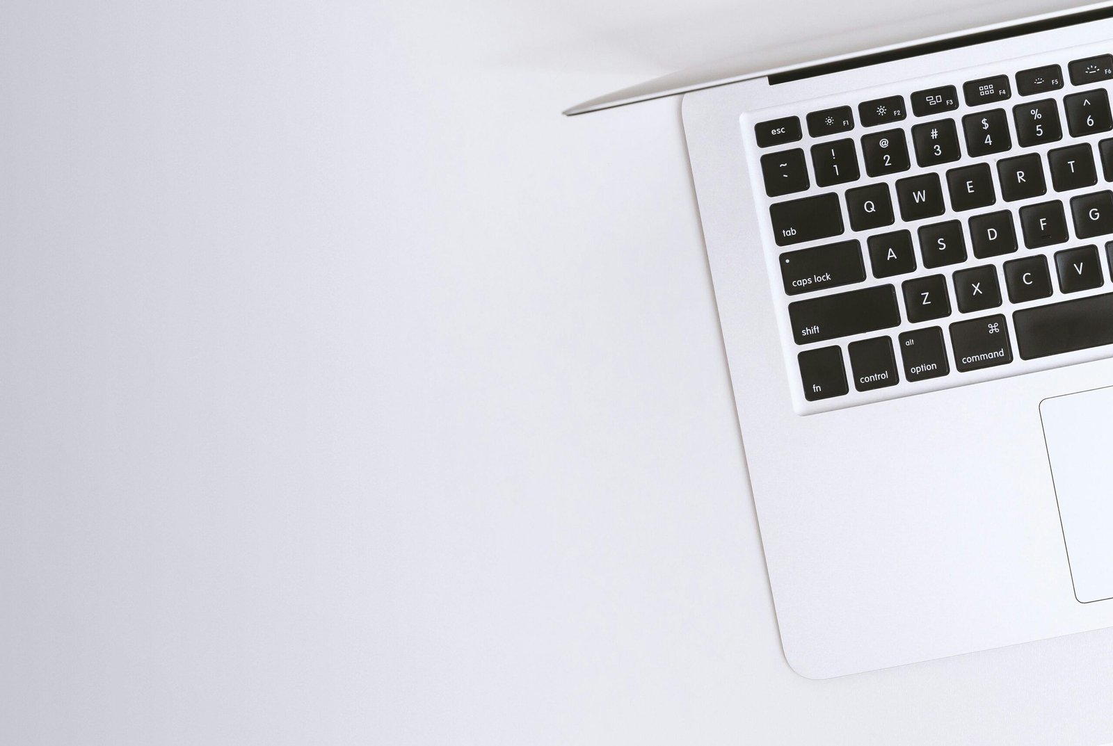 Aerial view of a sleek laptop keyboard on a clean, white surface, ideal for tech backgrounds.